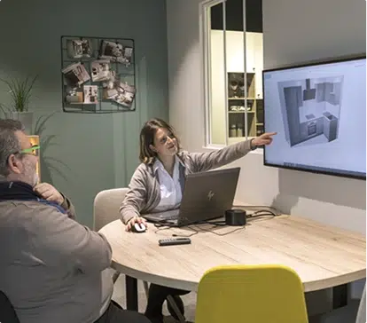 Asesor y clienta revisan el plano de la cocina en pantalla en una mesa redonda