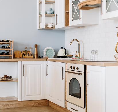 Cuisine moderne avec des placards blancs, des étagères ouvertes, un four encastré, et un comptoir en bois clair, décorée d'ustensiles et d'accessoires.