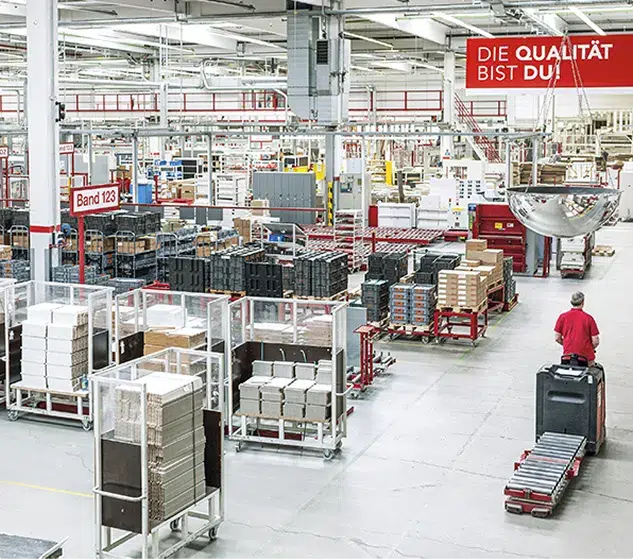 Fábrica de muebles de cocina con palés apilados y cartel «DIE QUALITÄT BIST DU!»