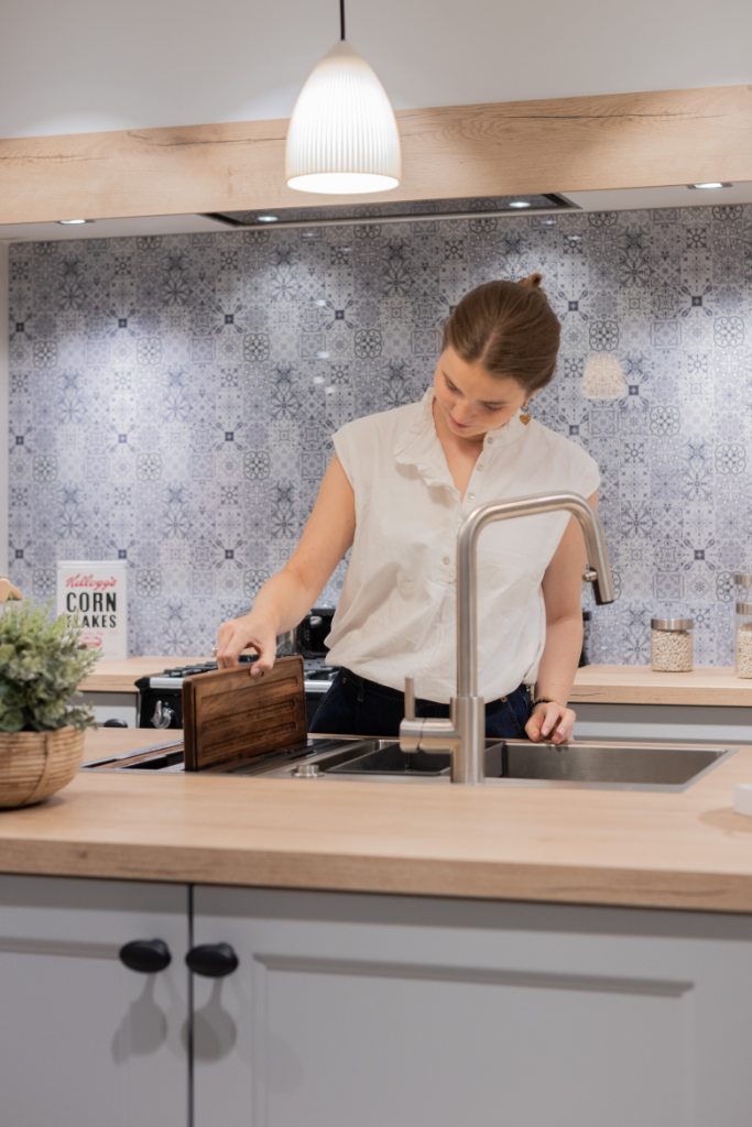 Mujer cortando sobre una tabla de madera en una cocina con azulejos azules estampados
