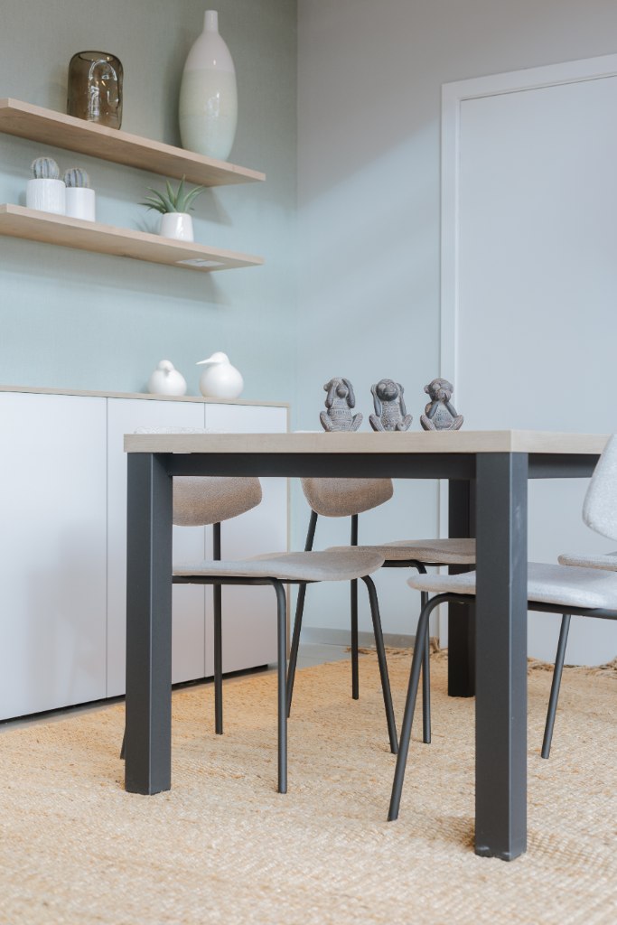 Mesa de comedor negra con sillas oscuras en una cocina blanca con estantes