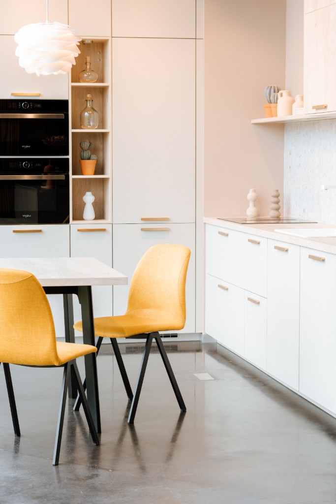 Cocina blanca con mesa de madera y sillas amarillas