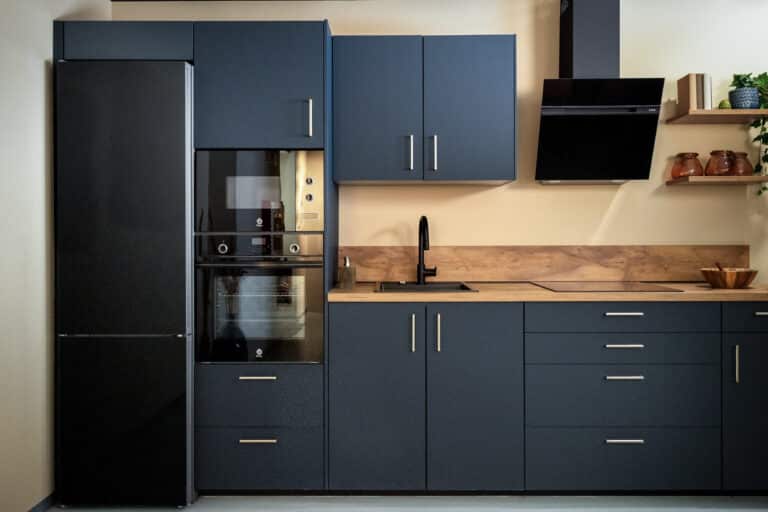 Cocina azul oscura con encimera de madera y horno en columna