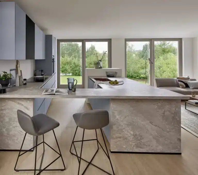 Cocina semiabierta con barra y dos taburetes junto al salón