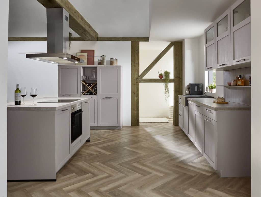 Cocina gris con isla, campana de acero y vigas de madera