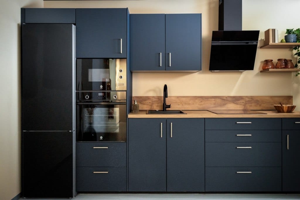 Cocina azul oscura con encimera de madera y horno en columna