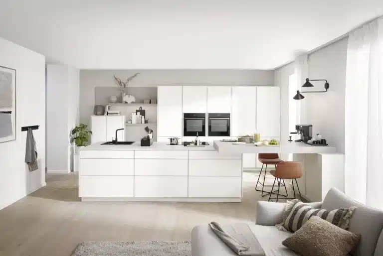 Cocina blanca con isla abierta a un salón luminoso