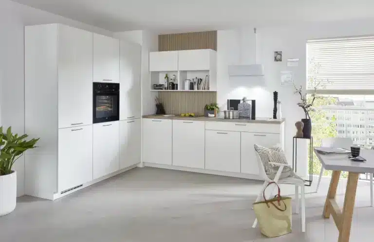 Cocina blanca en L con horno en columna y comedor