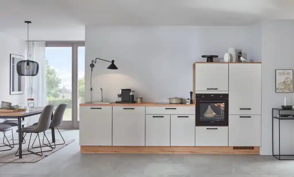 Cocina blanca lineal con encimera de madera y comedor
