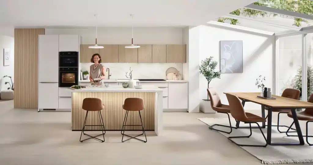 Cocina blanca y madera con isla abierta a un comedor luminoso